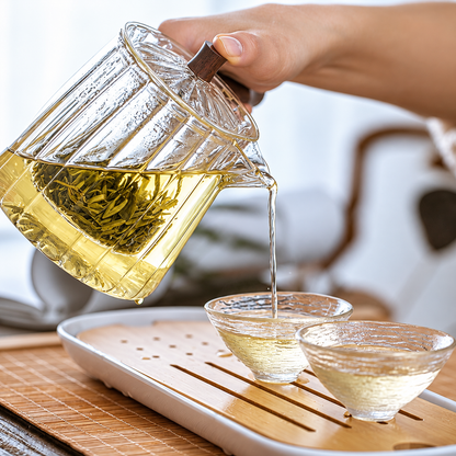 Jasmine tea being poured from a glass teapot into glass cups